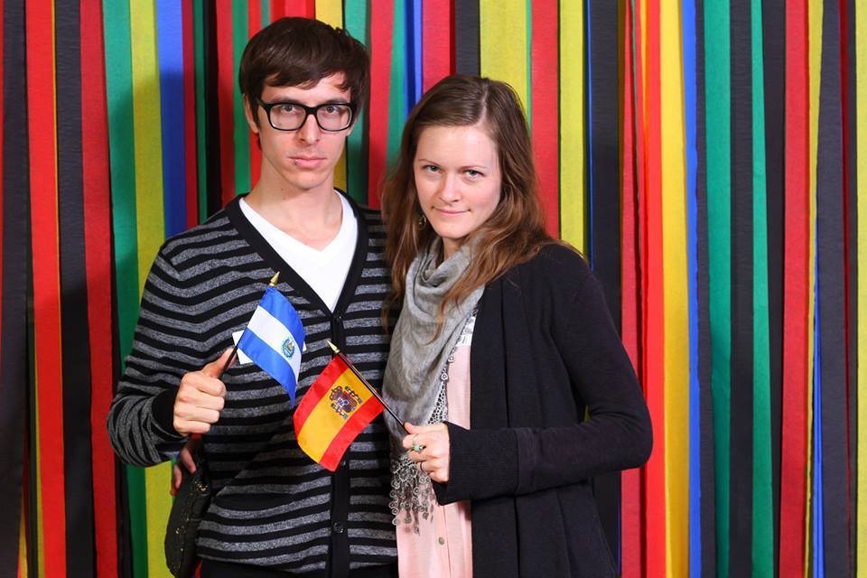 Man and woman smiling holding a El Salvador and Spanish flag